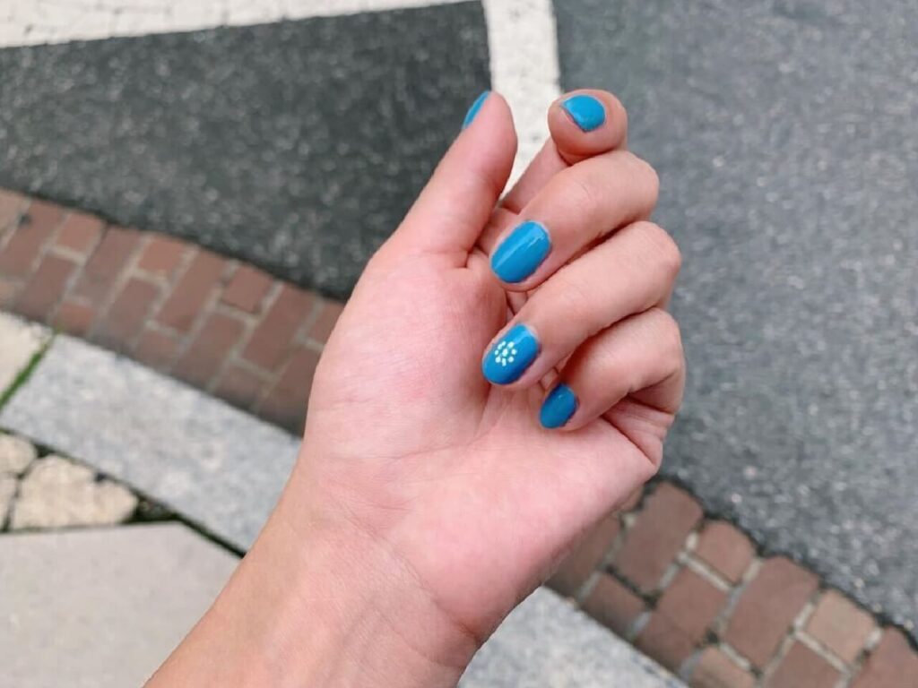 Cassandra’s hand shows off bright blue nail polish with a floral design, a playful detail that reflects her creativity and individuality as part of Bonterra’s diverse tech community.
