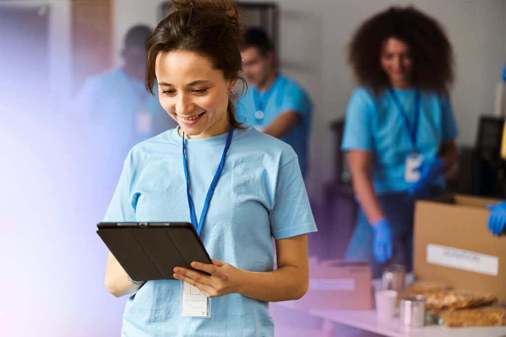 Two colleagues sitting at a table, smiling and looking at a laptop screen, representing collaboration and positive engagement in a shared workspace.