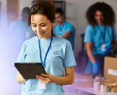 Two colleagues sitting at a table, smiling and looking at a laptop screen, representing collaboration and positive engagement in a shared workspace.