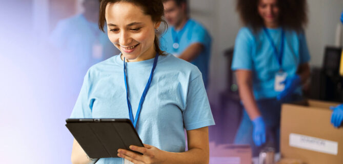 Two colleagues sitting at a table, smiling and looking at a laptop screen, representing collaboration and positive engagement in a shared workspace.