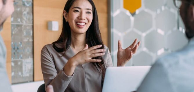 A team discusses information together during a meeting, with one person presenting ideas using a laptop.