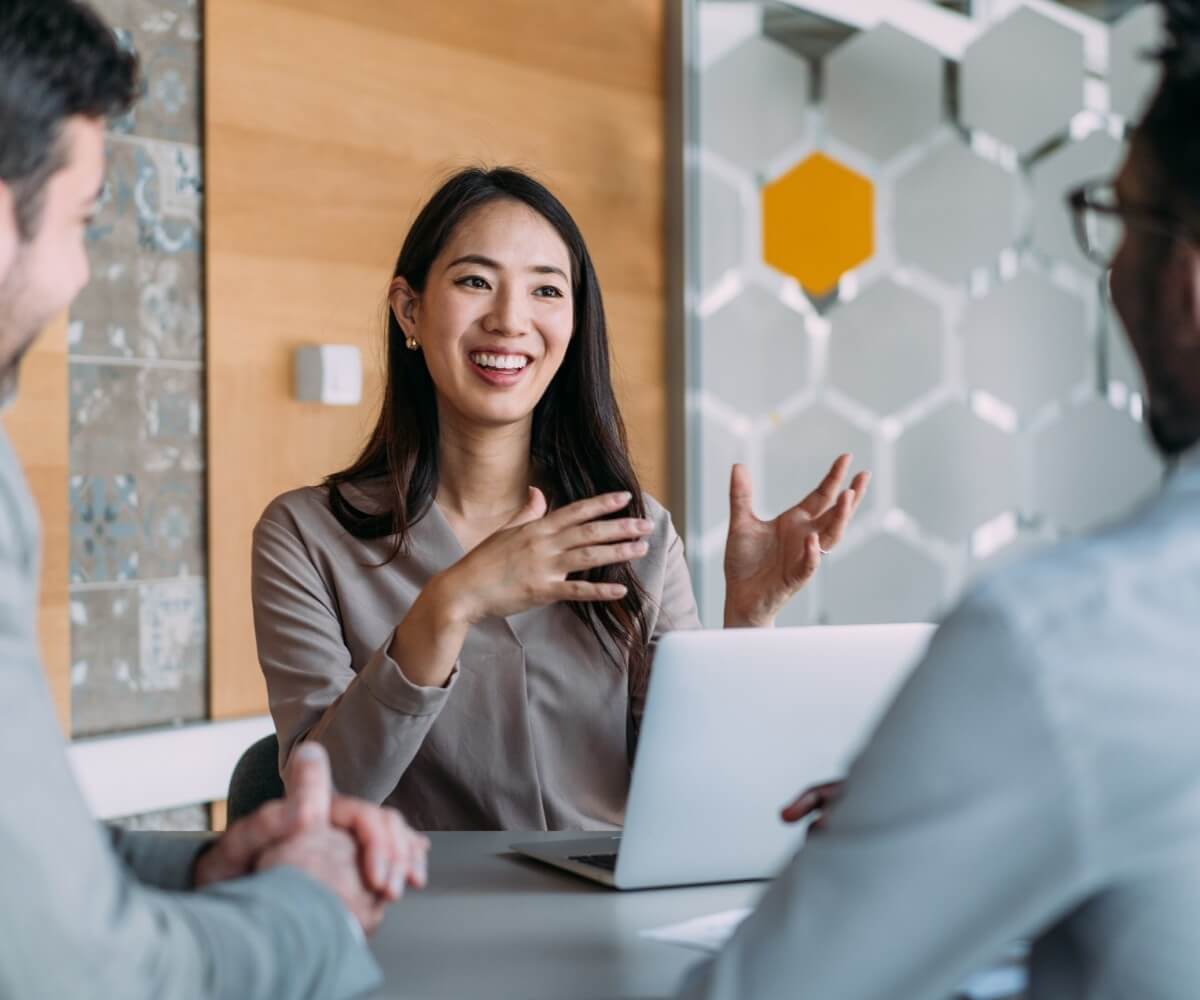 A team discusses information together during a meeting, with one person presenting ideas using a laptop.